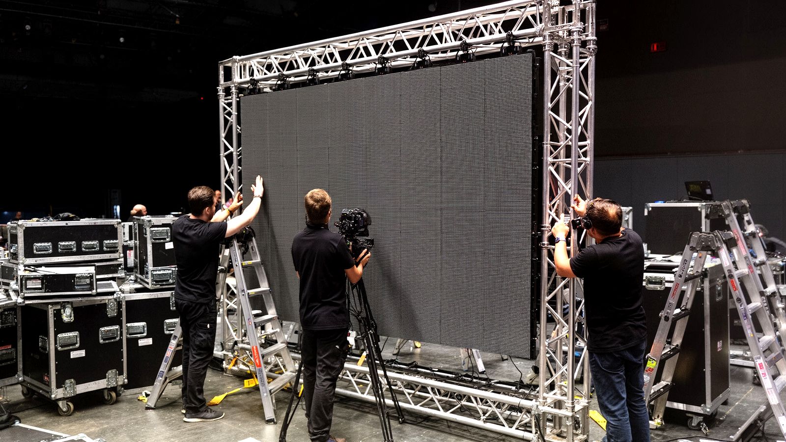 Technicians installing a large LED video wall on truss for an event